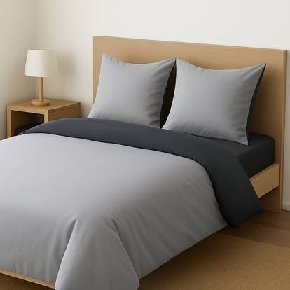 Modern bedroom with wood bed frame, gray bedding, two pillows, and wooden nightstand with white lamp